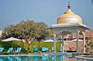 a gazebo next to a pool with chairs and umbrellas at Tree of Life Resort & Spa Jaipur in Jaipur