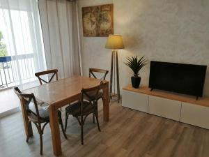 a living room with a wooden table and a television at GRAU DU ROI T2 calme, accès plage + parking in Le Grau-du-Roi