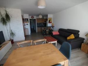 a living room with a table and a couch at GRAU DU ROI T2 calme, accès plage + parking in Le Grau-du-Roi