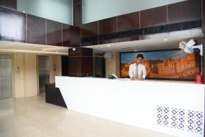 a reception counter in a lobby with a picture of a man at Broadway Inn in Jaipur