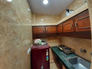 a small kitchen with a red refrigerator and a sink at Cream Location,wifi With Android Tv, Luxury Room in New Delhi