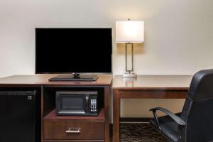 a television on a desk with a microwave and a lamp at La Quinta by Wyndham Clearwater Central in Clearwater
