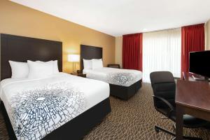 a hotel room with two beds and a desk at La Quinta by Wyndham Clearwater Central in Clearwater