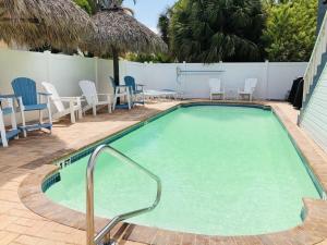 a large swimming pool with chairs and tables and chairs at Amazing beach getaway pool condo by the beach in Bradenton Beach