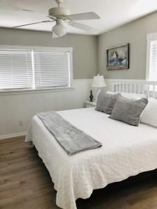 a bedroom with a white bed with a ceiling fan at Amazing beach getaway pool condo by the beach in Bradenton Beach +19 photos