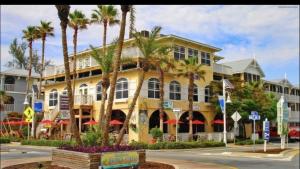 a yellow building with palm trees in front of it at Amazing beach getaway pool condo by the beach in Bradenton Beach