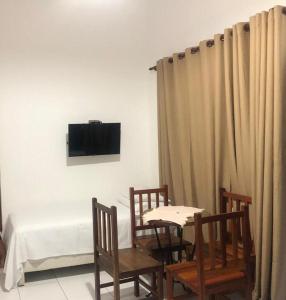 um quarto com uma mesa e cadeiras e uma televisão em CHALÉ da LÚ ILHABELA em Ilhabela