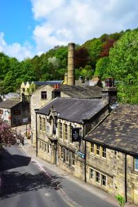 um antigo edifício de pedra ao lado de uma rua em White Lion em Hebden Bridge