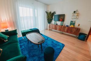 een woonkamer met een groene bank en een blauw tapijt bij Aupark Apartment Peacock in Piešťany