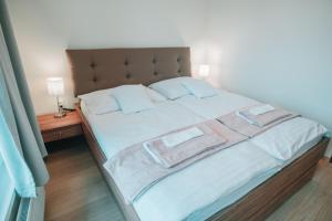 a bedroom with a large bed with white sheets and blue pillows at Aupark Apartment Peacock in Piešťany