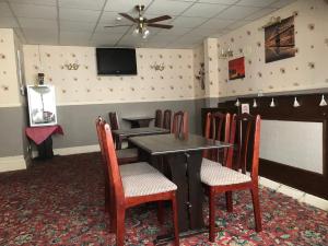 een eetkamer met een tafel en stoelen en een televisie bij Melrose Hotel in Blackpool