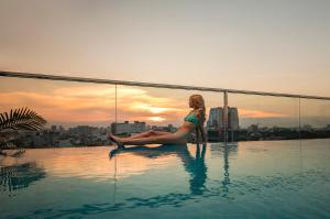 a woman sitting on the edge of a swimming pool at Soleil Boutique Hotel Hanoi in Hanoi