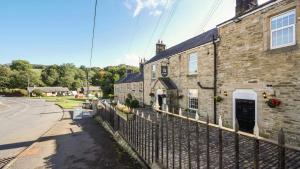 un edificio de ladrillo con una valla al lado de una calle en The Greenhead Hotel, en Greenhead