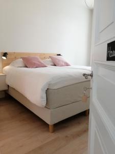 Schlafzimmer mit einem Bett mit weißer Bettwäsche und rosa Kissen in der Unterkunft Haven 7 in Brügge