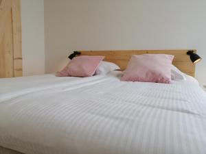 een wit bed met twee roze kussens erop bij Haven 7 in Brugge