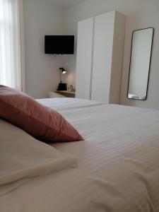uma cama branca com uma almofada vermelha num quarto em Haven 7 em Bruges