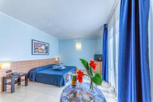 - une chambre avec un lit et une table ornée d'un vase de fleurs dans l'établissement Hotel Le Torri, à Arborea