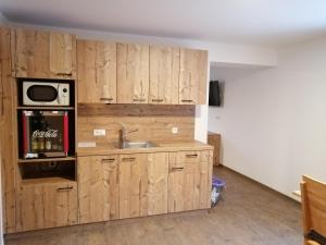 cocina con armarios de madera, fregadero y microondas en Hansmayrgut, en Waizenkirchen