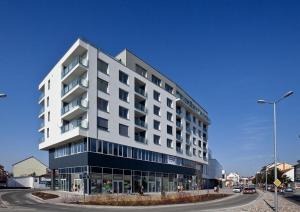 a large white building on the corner of a street at Aupark Apartment Peacock in Piešťany