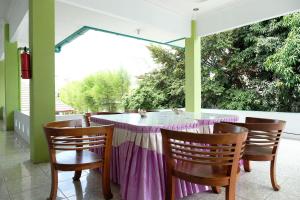uma mesa com uma toalha de mesa roxa e três cadeiras em OYO 2186 Esbe Hotel Syariah em Tanjungpandan