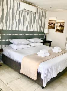 a bedroom with a large bed with white pillows at Studio on Albert, Hout Bay in Hout Bay