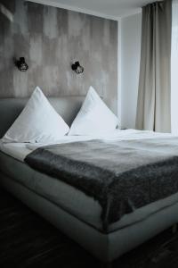 Una cama con sábanas blancas y almohadas en un dormitorio en Excellentas Apartments Hannover, en Hannover