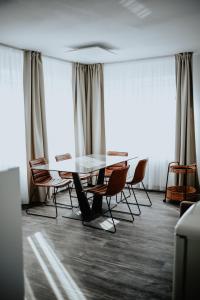 une table et des chaises dans une pièce avec fenêtres dans l'établissement Excellentas Apartments Hannover, à Hanovre