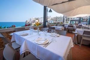 un restaurante con mesas y sillas blancas y el océano en Covo dei Saraceni, en Polignano a Mare