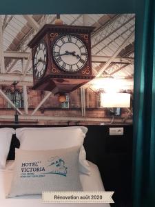 a clock hanging over a bed with a pillow at Hotel Victoria Lyon Perrache Confluence in Lyon