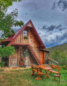 a wooden cabin with a picnic table and a bench at Log cabin Uvac (Vikendica Saponjic) in Nova Varoš