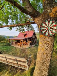 a house with a dart board hanging from a tree at Log cabin Uvac (Vikendica Saponjic) in Nova Varoš