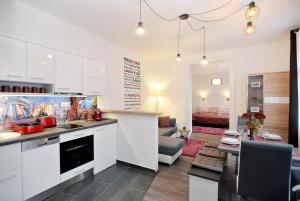 a kitchen with white cabinets and a living room at Nobilis Apartman Eger in Eger