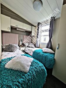 a bedroom with two beds with blue blankets at Tattershall Luxury Hot Tub Caravan in Tattershall