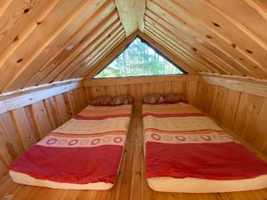 two beds in a wooden cabin with a window at Viking house in the tree! Jacuzzi, Sauna,apkure! in Līči