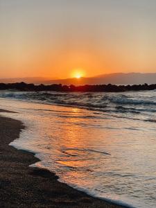 the sun is setting on the beach near the ocean at Vergina Beach Hotel in Agia Marina Nea Kydonias