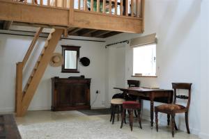 a room with a wooden table and a wooden staircase at Baptist Cottage in Cheverell