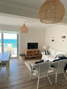 un salon avec un canapé blanc et une télévision dans l'établissement Balcony Beach Apartment • BBA • Moledo, à Moledo