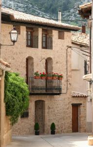 a building with a balcony with red flowers on it at Casa Morató in Beceite