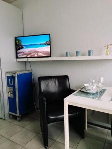 オーステンデにあるModern studio direct Seaview & free parkingの黒い椅子とテーブル、そして壁に掛かったテレビ