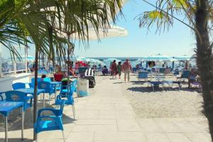 a beach with blue chairs and people on the sand at Cortina 1-83 in Lido di Pomposa