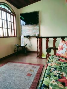 a bedroom with a bed and a flat screen tv at Aconchego de Regina in Tiradentes