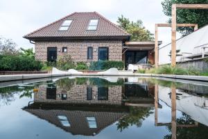 een huis met een reflecterend zwembad ervoor bij Loft 8 Linden in Groot-Linden