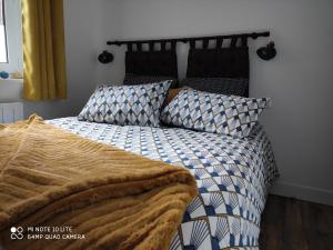 a bed with a black and white comforter and pillows at L' ALBATROS vue sur le port in Fécamp