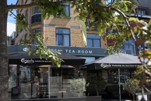 un salón de té con sombrillas frente a un edificio en Hotel Cecil, en De Panne