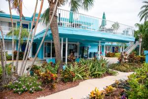 a blue building with palm trees and flowers at Bayside Inn and Marina in St Pete Beach