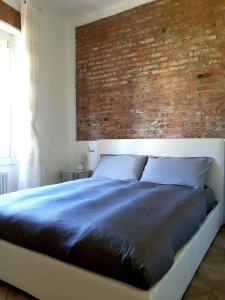 łóżko w sypialni z ceglaną ścianą w obiekcie Il Melo Antico - appartamenti in villa d'epoca nel cuore del Monferrato w mieście Acqui Terme