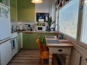 a kitchen with green cabinets and a table with a microwave at Torni-Mänttä in Mänttä