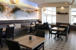 a restaurant with tables and chairs and a couch at Hotel Cecil in De Panne