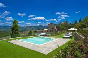 une piscine au milieu d'une pelouse avec une maison dans l'établissement Amore Rentals - Villa delle Donne, à Panzano