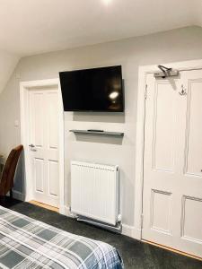 a bedroom with a flat screen tv on the wall at MacArthur House NC500 in Wick